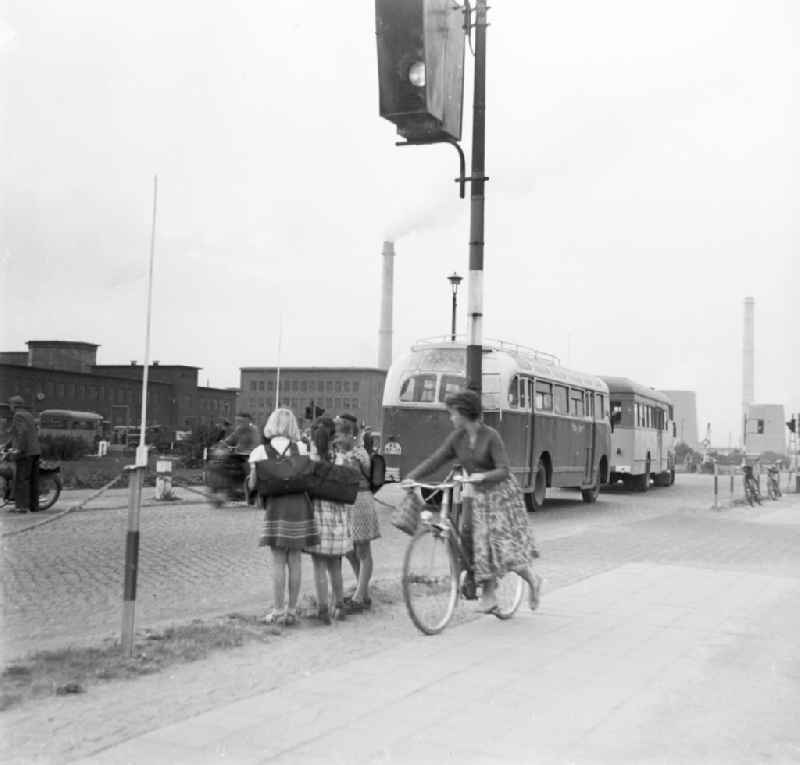 Girls with school bag stand in the street edge and observe the traffic in Schkopau in the federal state Saxony-Anhalt in the area of the former GDR, German democratic republic