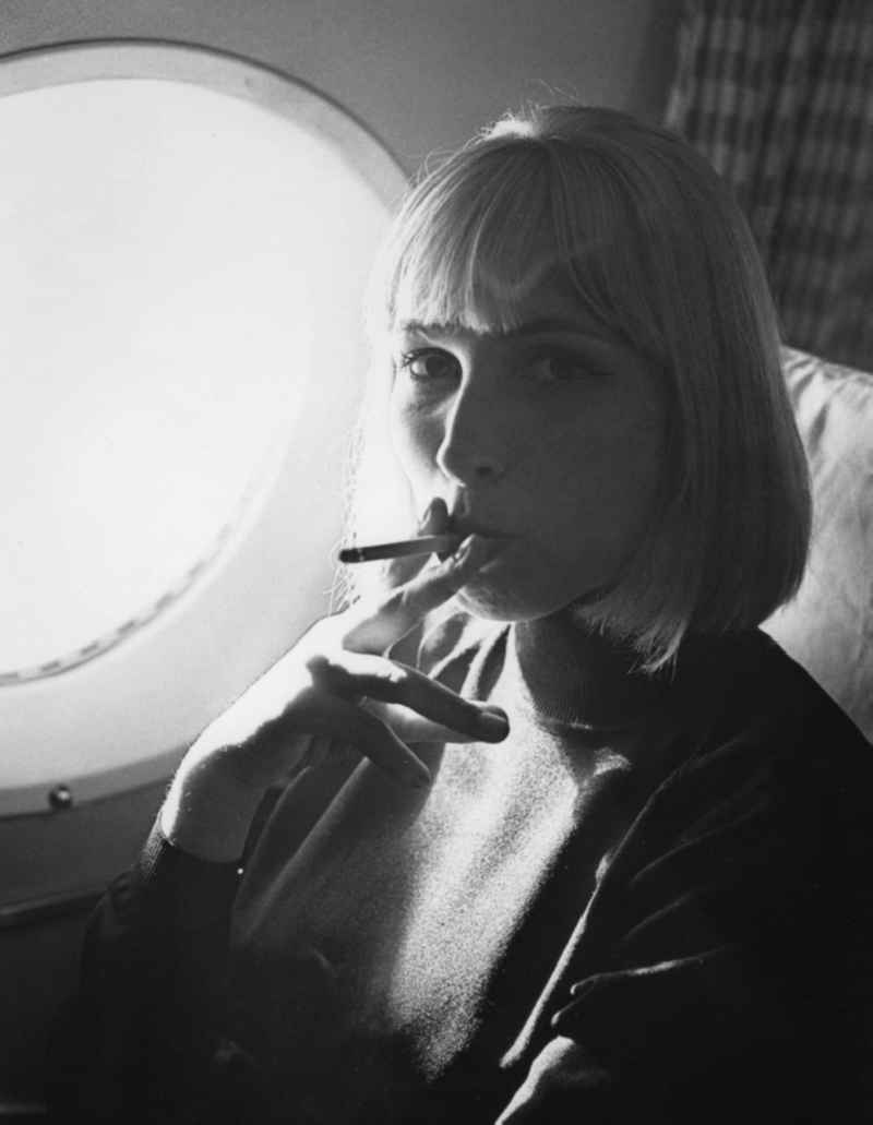 Vera Oelschlegel, a German singer, actress, director, professor and theater director sitting in an airplane and smokes