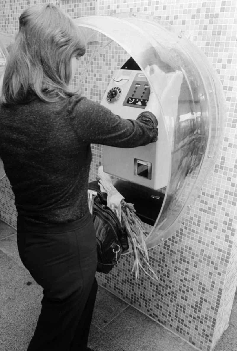 A woman calls up a pay phone in the railway station airport Berlin-Schoenefeld in Schoenefeld in the federal state Brandenburg in the area of the former GDR, German democratic republic