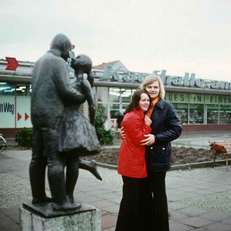 Ein junges Paar posiert vor der Skulptur 'Liebespaar' des Künstlers Axel Schulz, die vor einer Kaufhalle steht. Durch die Errichtung einer Papierfabrik und des Erdölverarbeitungswerks Schwedt (heute PCK Raffinerie) in den 1960er Jahren wuchs die Einwohnerzahl innerhalb von 15 Jahren von 10000 auf 4000