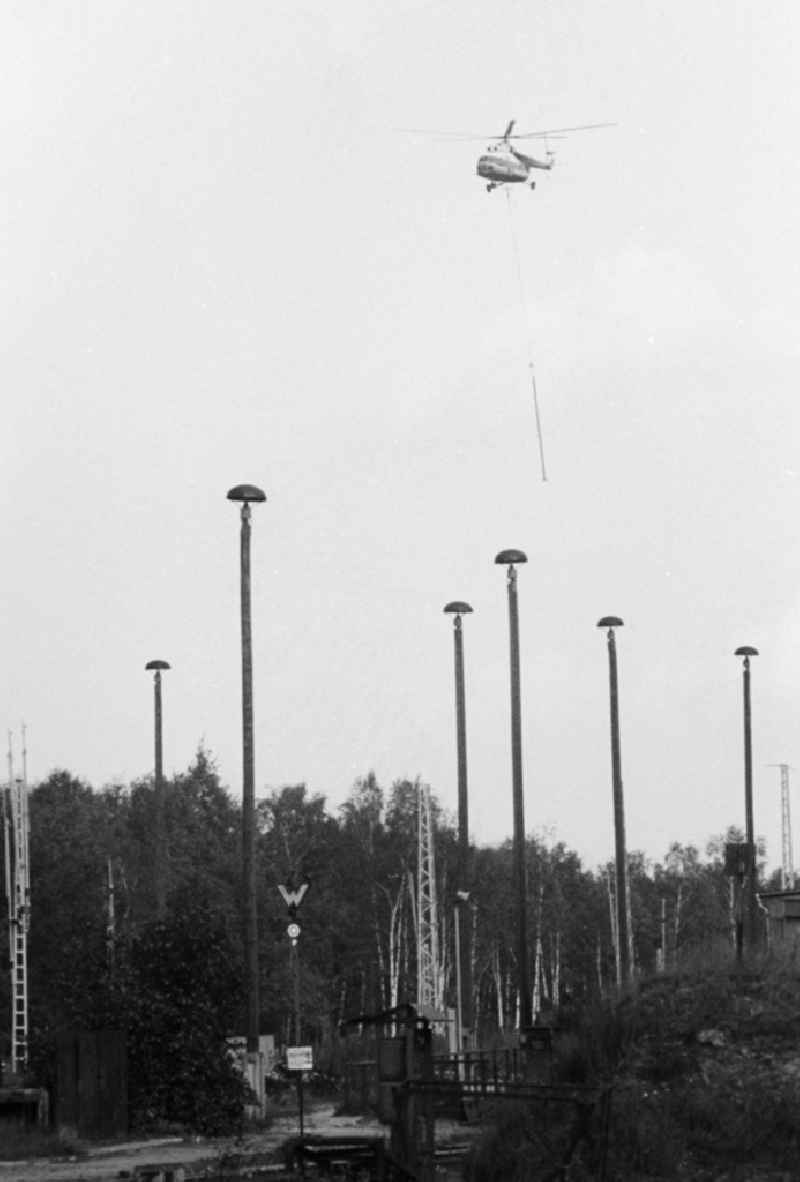 A transport helicopter of the type Mi8 transports driving poles to the railway station Seddin of the German national railway in Seddiner See in the federal state Brandenburg in the area of the former GDR, German democratic republic