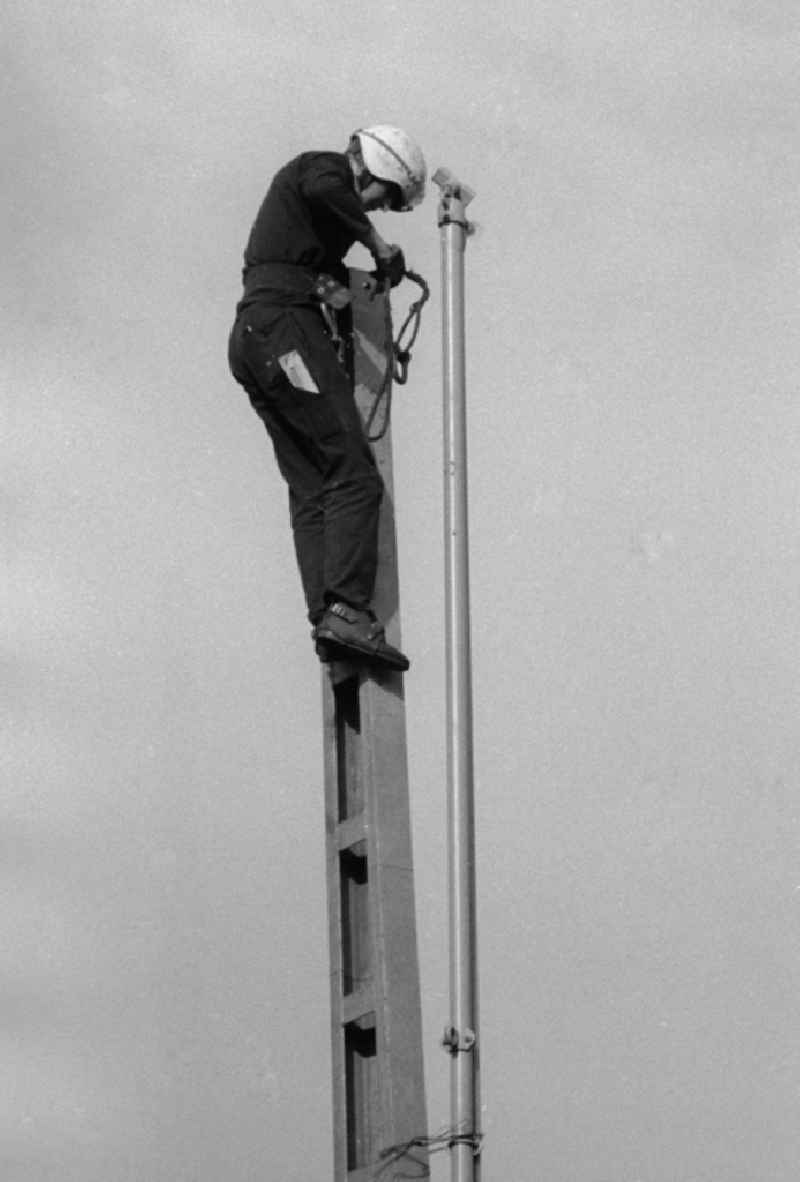 An employee of the German national railway mounts to driving poles in the railway station Seddin the direction in Seddiner See in the federal state Brandenburg in the area of the former GDR, German democratic republic