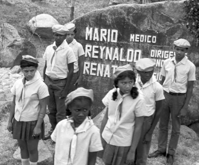 Zur Besichtigung der Granjita Siboney - einer Kultstätte der kubanischen Revolution - durch den Staats- und Parteivorsitzenden der DDR, Erich Honecker, stehen kubanische Pioniere an kleinen Denkmälern, die entlang der Straße zwischen Santiago de Cuba und Siboney zur Erinnerung an die beteiligten Revolutionäre aufgestellt sind. Die ehemalige Hühnerfarm hatte 1953 den Rebellen um Fidel Castro während der Planung des Sturms auf die Moncada-Kaserne in Santiago als Versteck gedient. Hier waren gefälschte Soldatenuniformen genäht und in einem trockenen Brunnen Waffen versteckt worden. - Honecker stattete vom 2