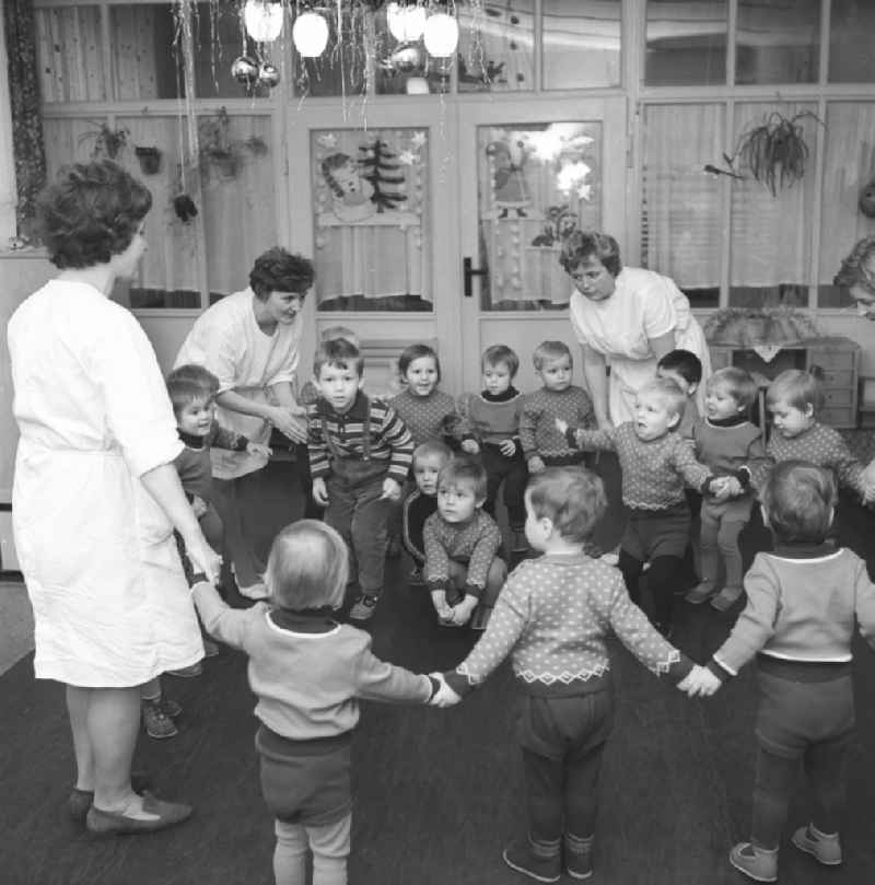Everyday life in a baby cot in Silbitz in today s state of Thuringia. Children standing togetherwith nursery nurse in white coats in a circle