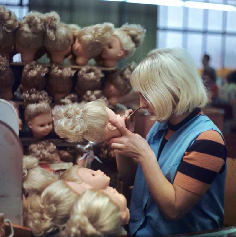 Eine Mitarbeiterin des VEB Kombinat Spielwaren Sonneberg 'sonni' verschönert die fertiggestellten Puppenköpfe mit sicher geführtem Pinselstrich, aufgenommen 1973. Die Sonneberger Puppen waren nicht nur in der DDR beliebt, sondern trugen den Namen der Stadt in alle Welt.