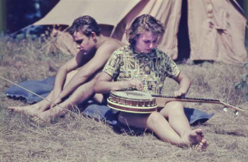 Summer camp operation with pupils and teenagers with an air mattress in front of a tent in Menz, Brandenburg on the territory of the former GDR, German Democratic Republic