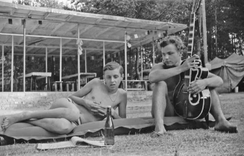 Summer camp operation with pupils and teenagers with guitar on an air mattress in Menz, Brandenburg on the territory of the former GDR, German Democratic Republic