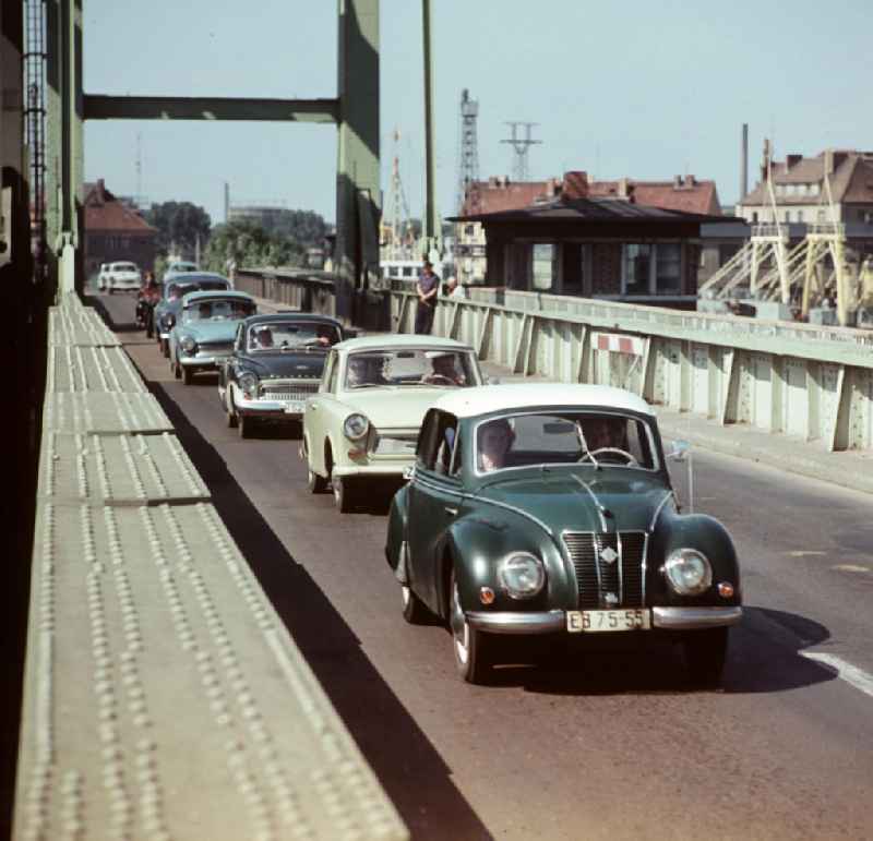 Autos überqueren die zum alten Rügendamm gehörende Ziegelgrabenbrücke, im Hintergrund die Altstadt von Stralsund. Die Ziegelgrabenbrücke als Teil des alten Rügendamms war eine Zugbrücke, die der Schifffahrt das Passieren des Rügendamms ermöglichte. Sie war zu festgelegten Zeiten für den Straßen- und Schienenverkehr gesperrt.