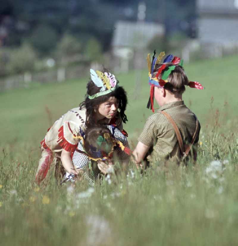 Kinder spielen auf einer Wiese bei Stützerbach Cowboy und Indianer.