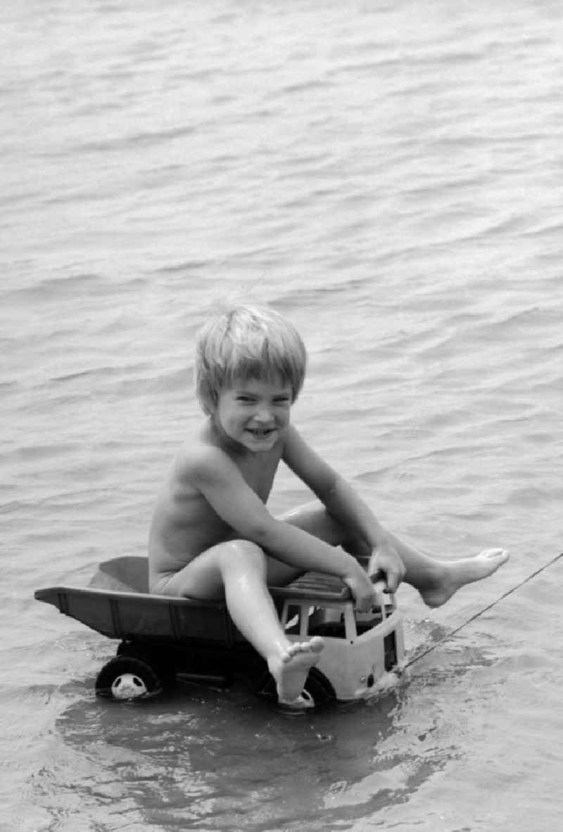 Boy on a plastic truck in water at Teupitzer lake in Teupitz in Brandenburg on the territory of the former GDR, German Democratic Republic