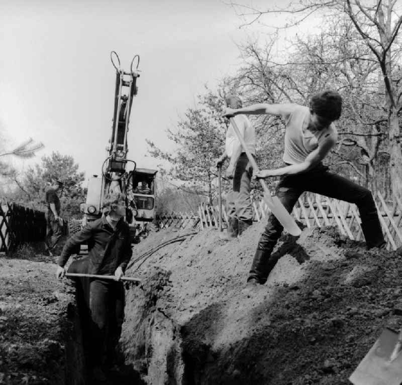 Garden owners and residents dig a cable trench together in Teupitz in the federal state of Brandenburg on the territory of the former GDR, German Democratic Republic