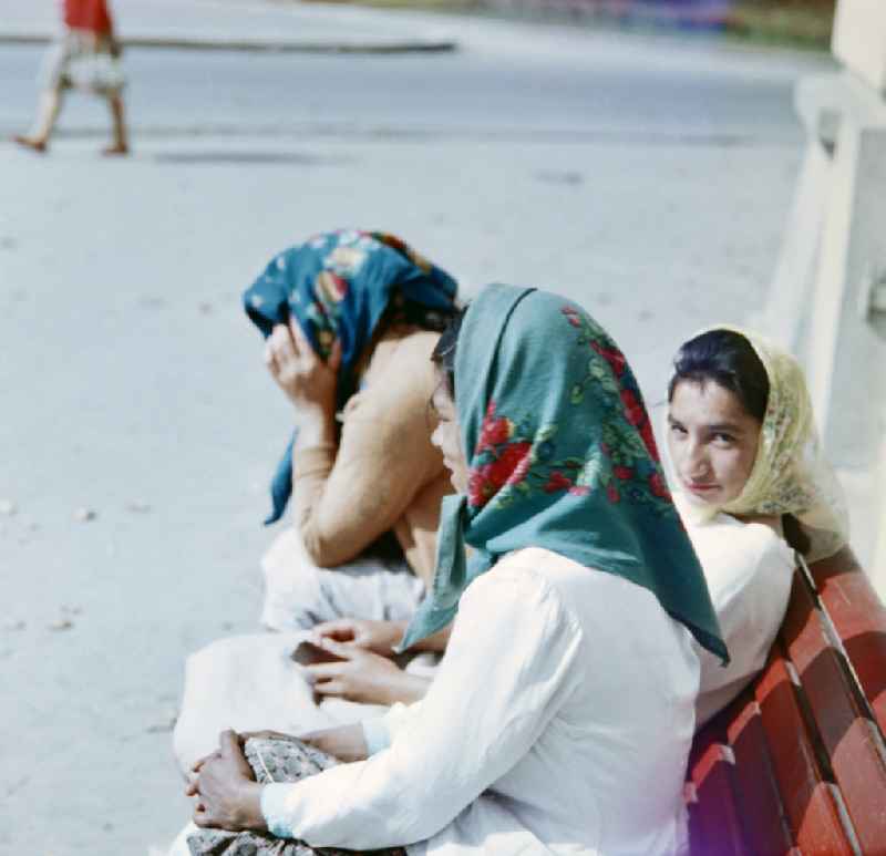 Three women are sitting on a bench in the former CSSR