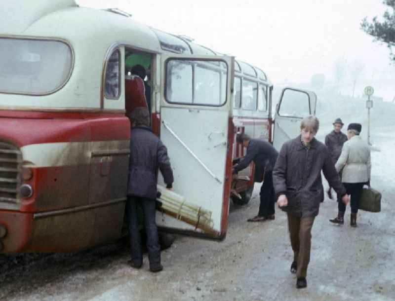 Passanten steigen an einer Haltestelle in einem Bu, vom Typ Ikarus 55, ein bzw. aus.