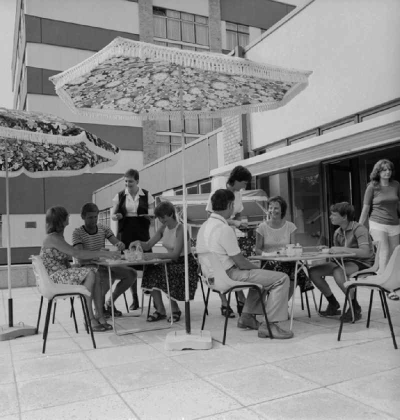 Guests drink coffee on the outdoor terrace under a parasol Somme in Ueckeritz in Mecklenburg-Western Pomerania in the field of the former GDR, German Democratic Republic