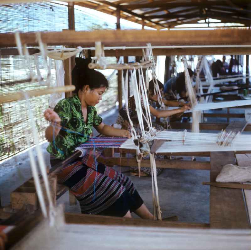 Frauen weben an Holzwebstühlen in einer Weberei in Vientiane, der Hauptstadt der Demokratischen Volksrepublik Laos.