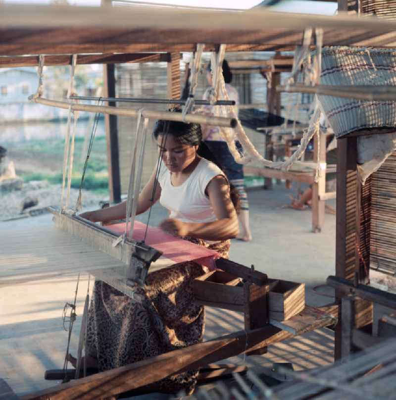 Eine Frau webt an einem Holzwebstuhl in einer Weberei in Vientiane, der Hauptstadt der Demokratischen Volksrepublik Laos.
