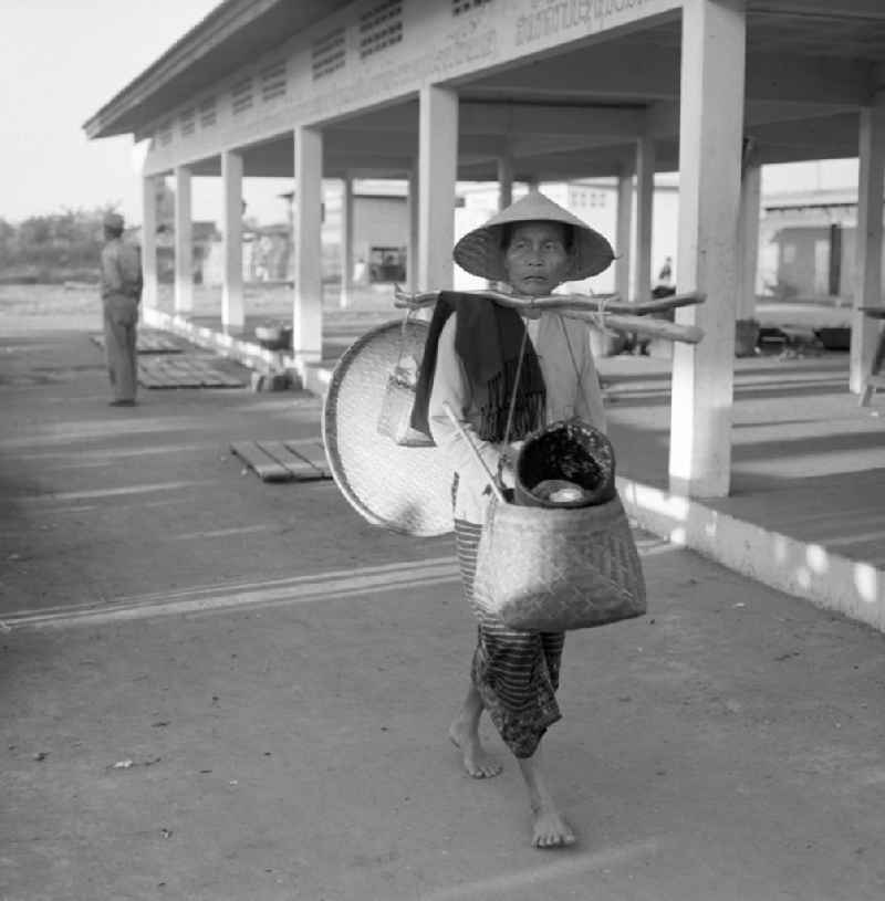 Eine Frau trägt geschulterte Körbe vor dem Markt in Vientiane, der Hauptstadt der Demokratischen Volksrepublik Laos.