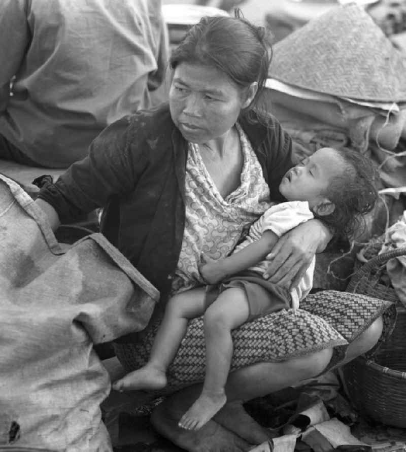Ein kleines Kind ist auf dem Arm seiner Mutter eingeschlafen - Marktszene in Vientiane, der Hauptstadt der Demokratischen Volksrepublik Laos.
