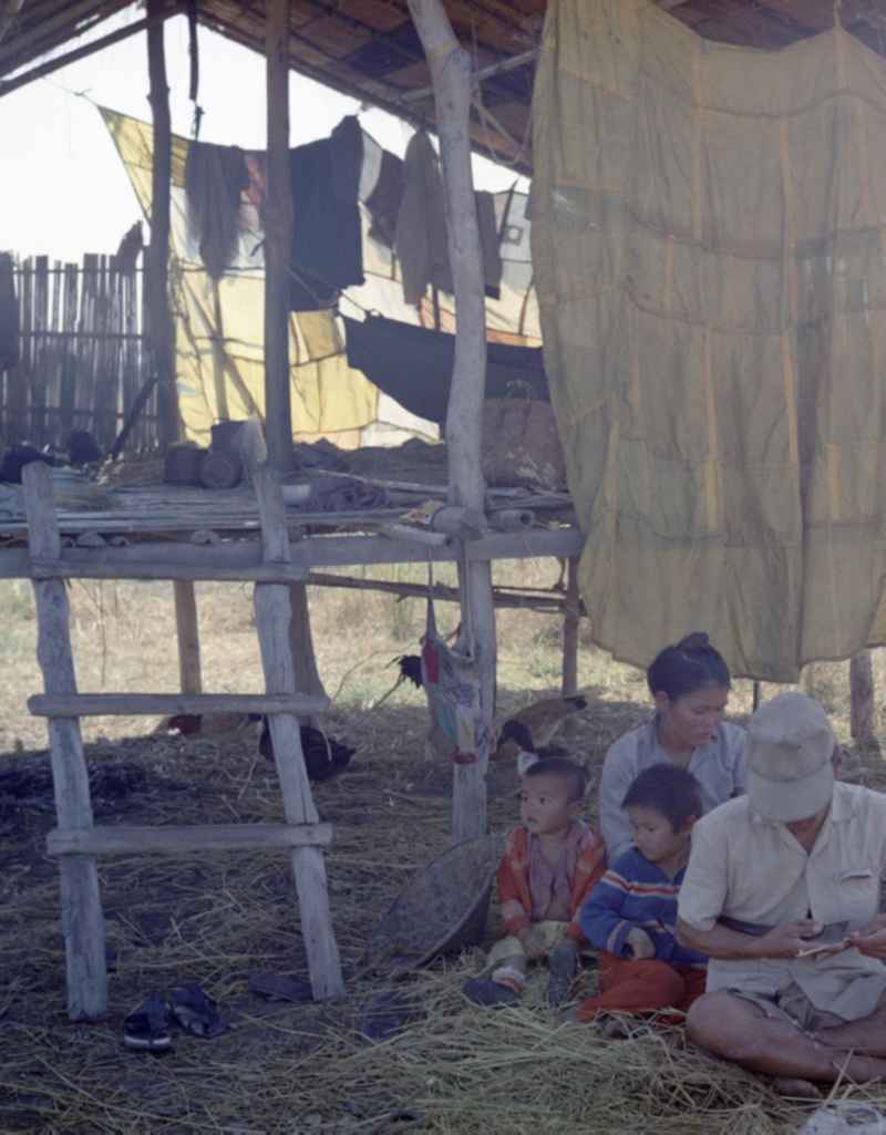 Männer, Frauen und Kinder sitzen während der Reisernte im Schatten einer Hütte auf einem Feld in der Demokratischen Volksrepublik Laos.