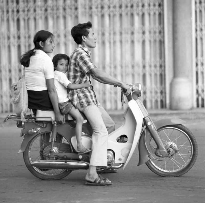 Die ganze Familie fährt mit auf einem Moped auf einer Straße in Vientiane, der Hauptstadt der Demokratischen Volksrepublik Laos.