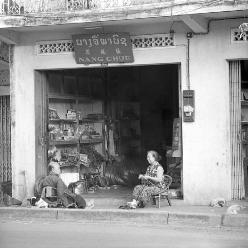 Zwei Frauen sitzen am Rand einer Straße vor einem Geschäft in Vientiane, der Hauptstadt der Demokratischen Volksrepublik Laos.