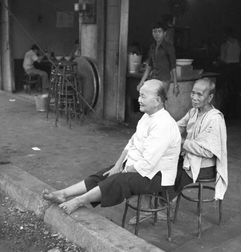 Zwei Frauen sitzen am Rand einer Straße in Vientiane, der Hauptstadt der Demokratischen Volksrepublik Laos.