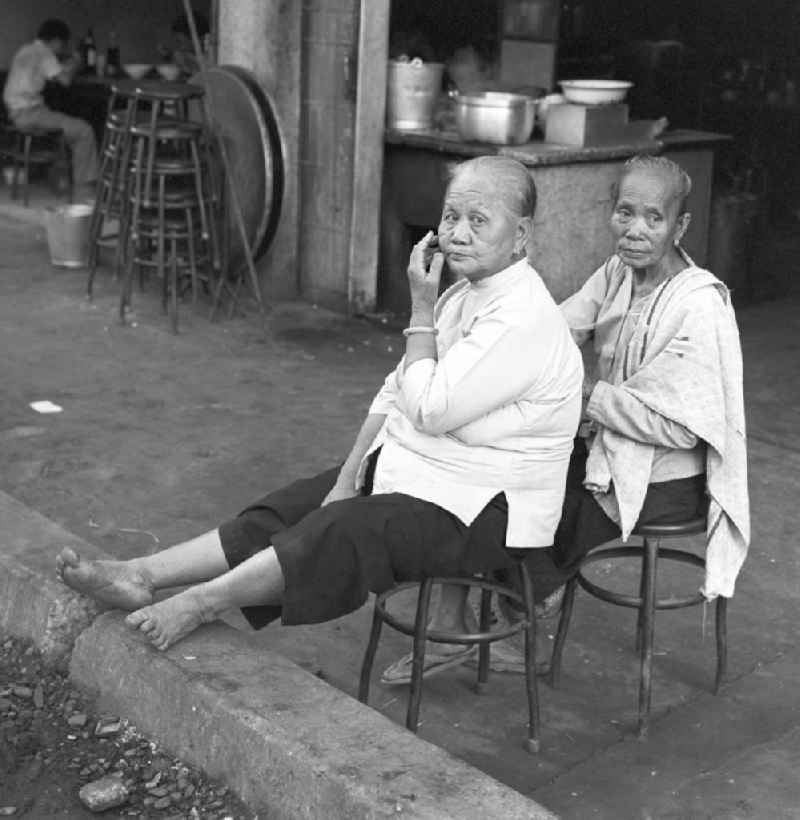 Zwei Frauen sitzen am Rand einer Straße in Vientiane, der Hauptstadt der Demokratischen Volksrepublik Laos.
