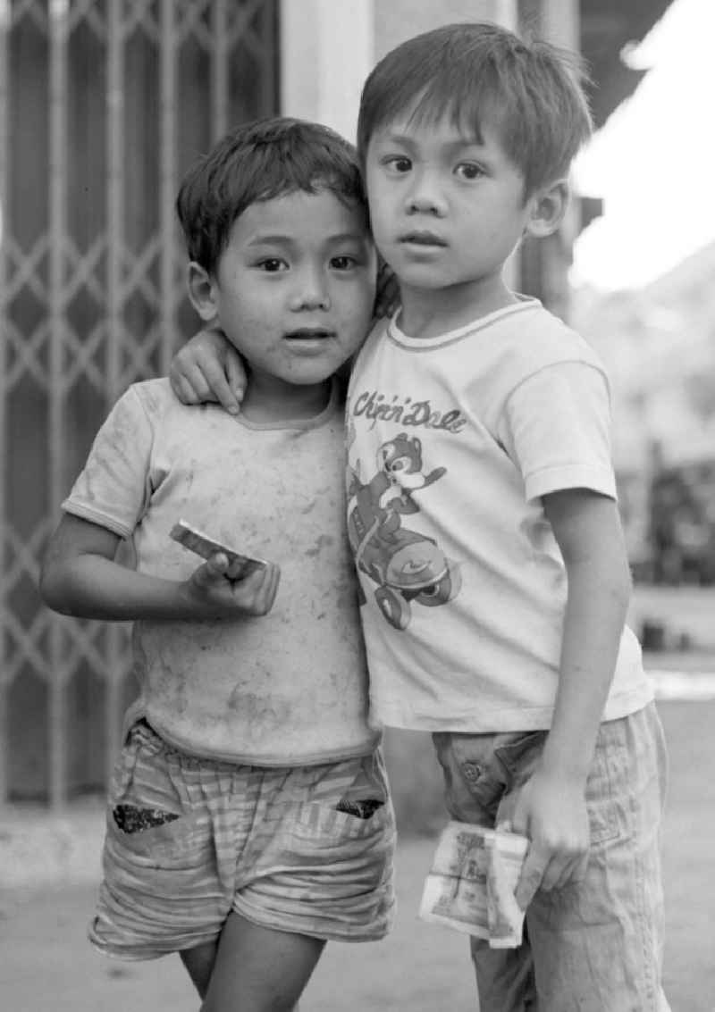 Zwei Kinder auf einer Straße in Vientiane, der Hauptstadt der Demokratischen Volksrepublik Laos. Ein Kind trägt ein T-Shirt mit den Chip 'n' Dale, zwei Trickfilmfiguren von Walt Disney.
