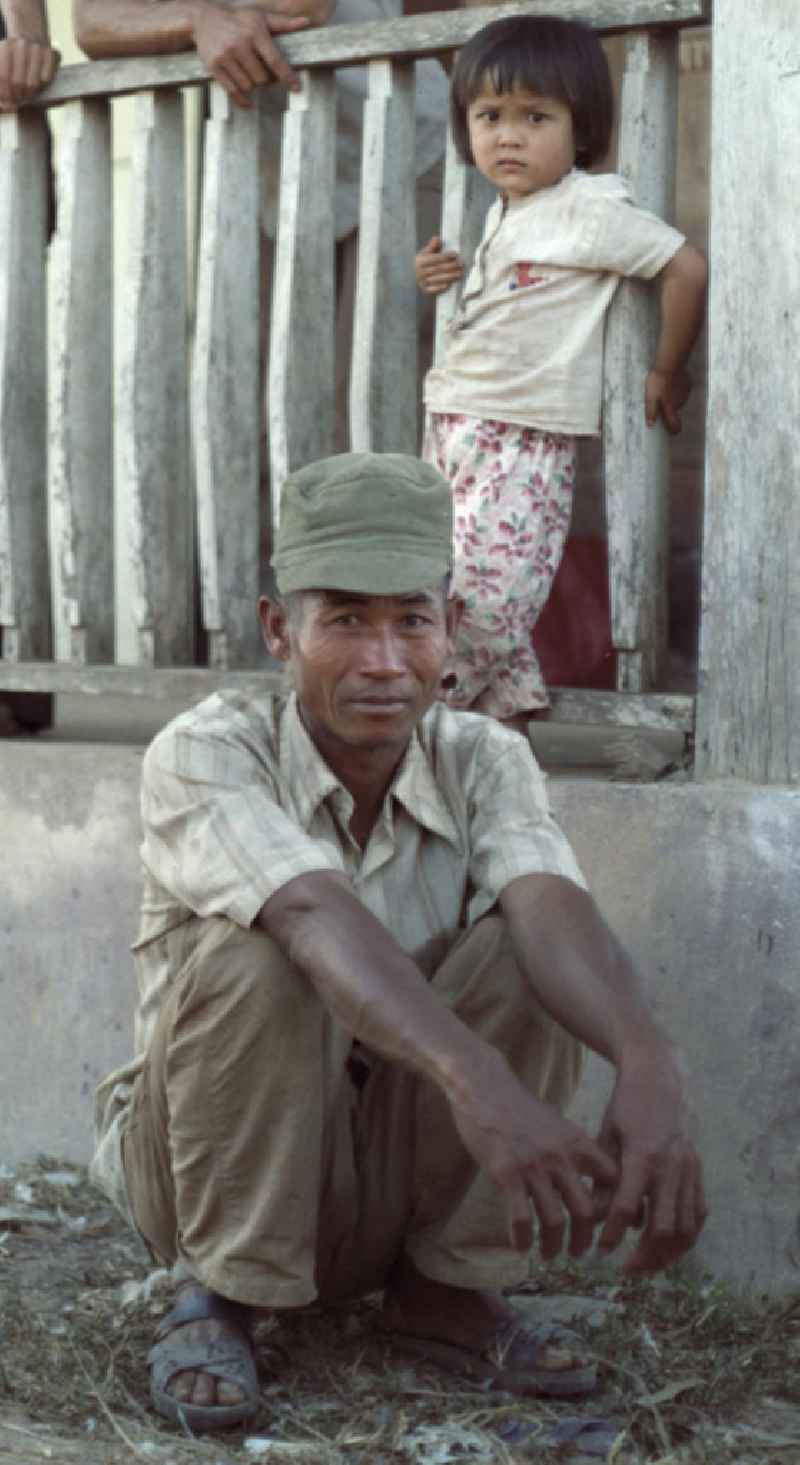 Mann mit Kind in einem Dorf in der Demokratischen Volksrepublik Laos.