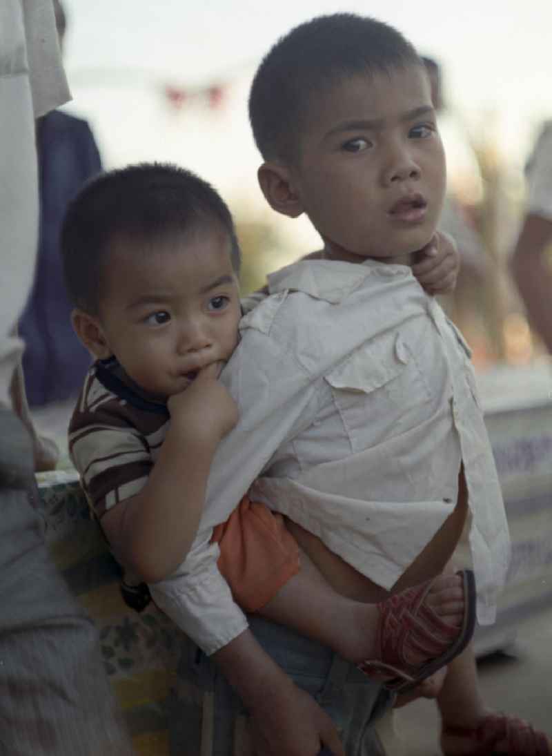 Ein Junge trägt seinen kleinen Bruder auf dem Rücken in einem Dorf in der Demokratischen Volksrepublik Laos.