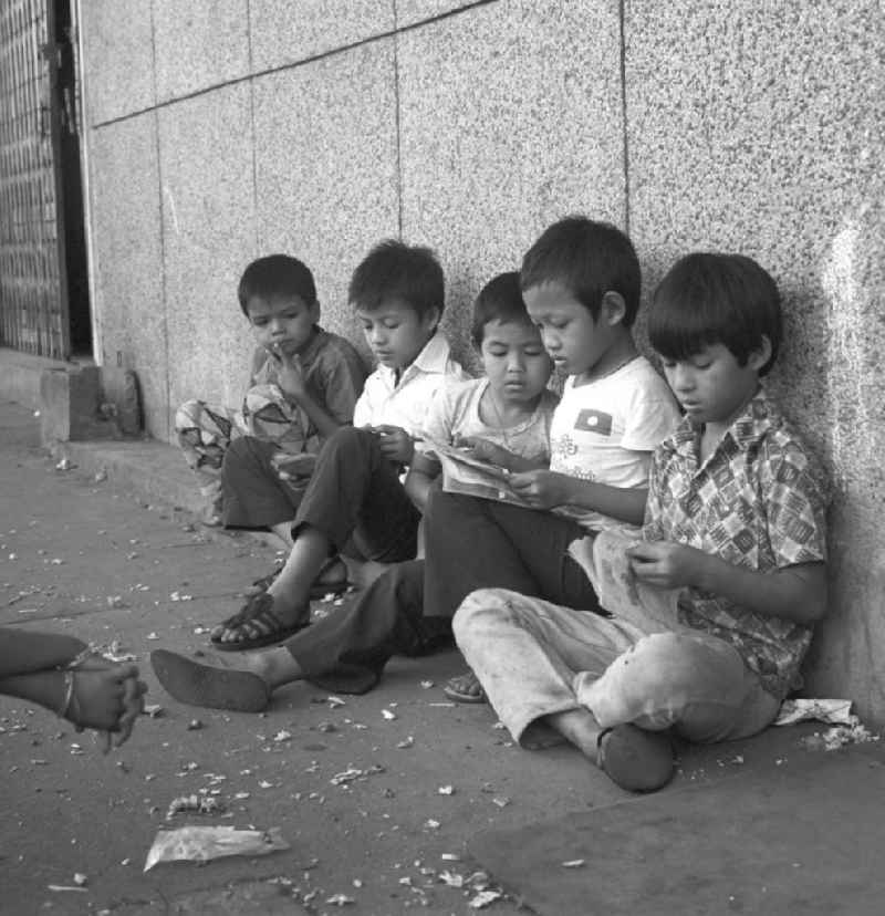 Kinder lesen am Rande des Marktes in Vientiane in der Demokratischen Volksrepublik Laos.