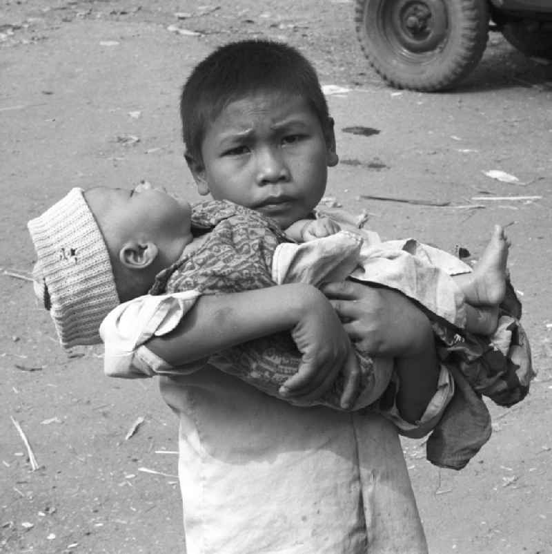Ein Junge hält seinen kleinen Bruder auf dem Arm auf einem Markt östlich von Vientiane in der Demokratischen Volksrepublik Laos.