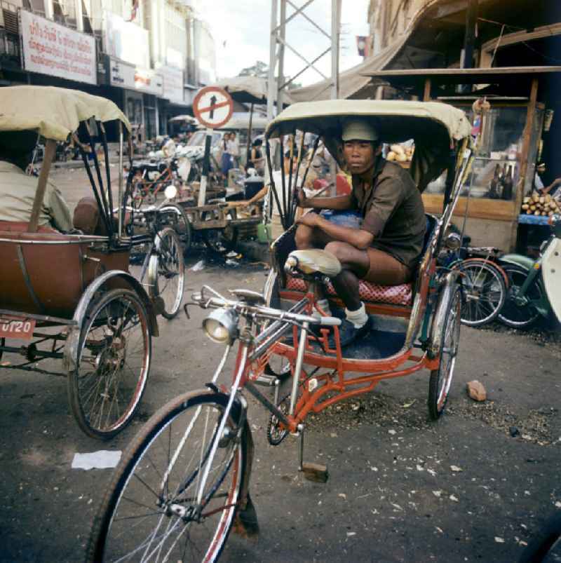 Rikschafahrer auf einer Straße in Vientiane in der Demokratischen Volksrepublik Laos.