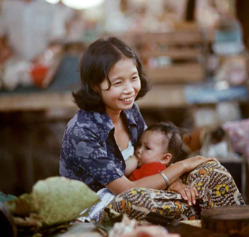 Eine Frau beim Stillen ihres Kindes auf einem Markt in Vientiane in der Demokratischen Volksrepublik Laos.