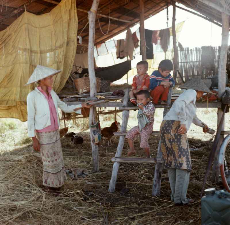 Frauen mit Kindern in ihrer Hütte während der Reisernte auf einem Feld in der Demokratischen Volksrepublik Laos.