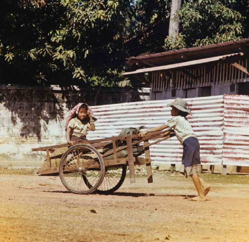Ein Mädchen schiebt einen beladenen Karren auf einer Straße in Vientiane in der Demokratischen Volksrepublik Laos.