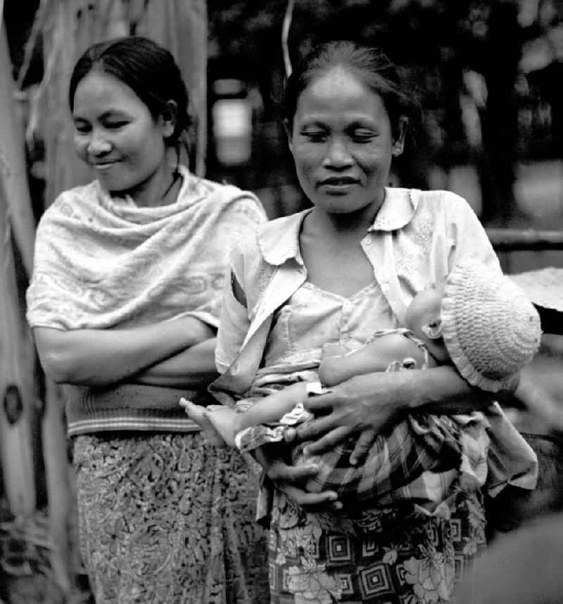 Eine Frau mit ihrem Baby auf dem Arm in einem Dorf in der Demokratischen Volksrepublik Laos.