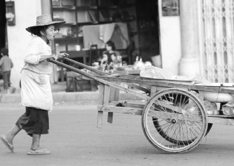 Eine alte Frau schiebt ihren Karren auf einer Straße in Vientiane in der Demokratischen Volksrepublik Laos.