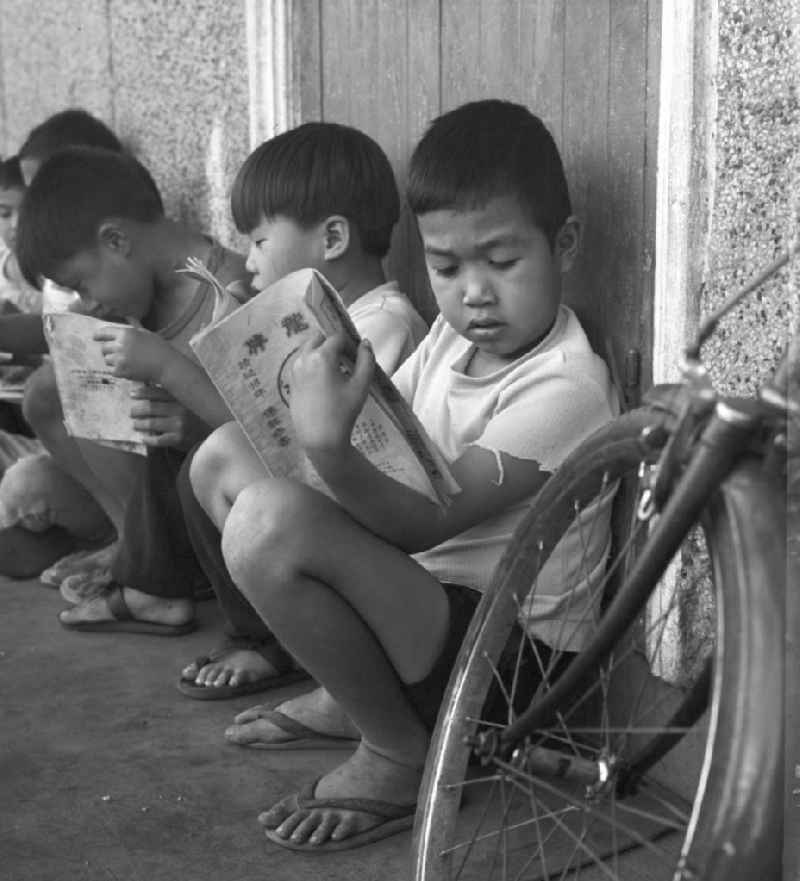 Kinder lesen am Rande des Marktes in Vientiane in der Demokratischen Volksrepublik Laos.