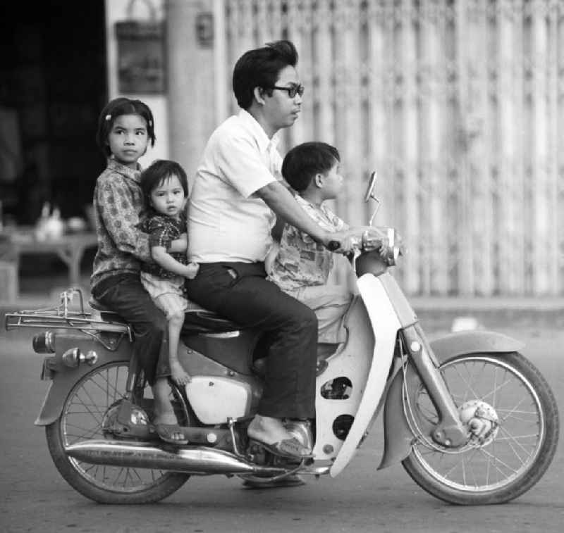 Ein Mann mit seinen Kindern auf einem Motorrad in Vientiane in der Demokratischen Volksrepublik Laos.