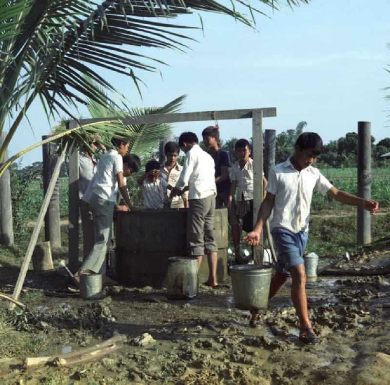 Kinder holen Wasser an einem Brunnen, um die Pflanzen in ihrem Schulgarten in einem Dorf in der Demokratischen Volksrepublik Laos zu bewässern.