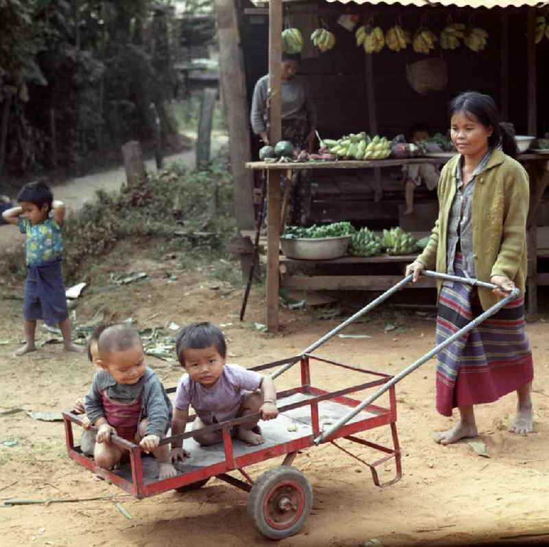 Frau mit Kindern in einem Dorf in der Demokratischen Volksrepublik Laos.