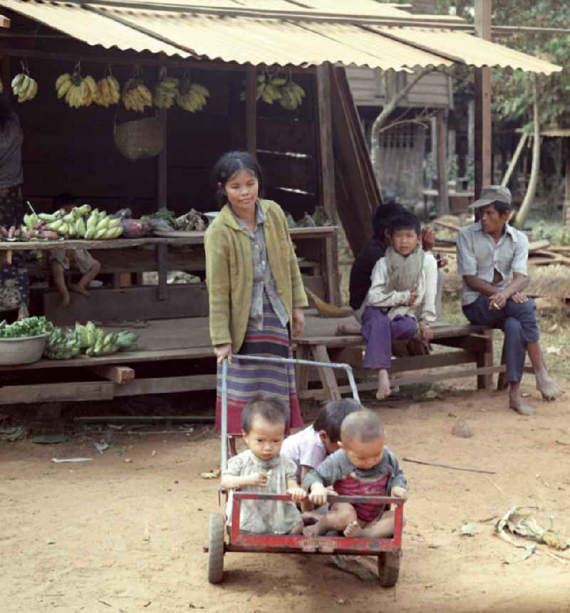 Frau mit Kindern in einem Dorf in der Demokratischen Volksrepublik Laos.