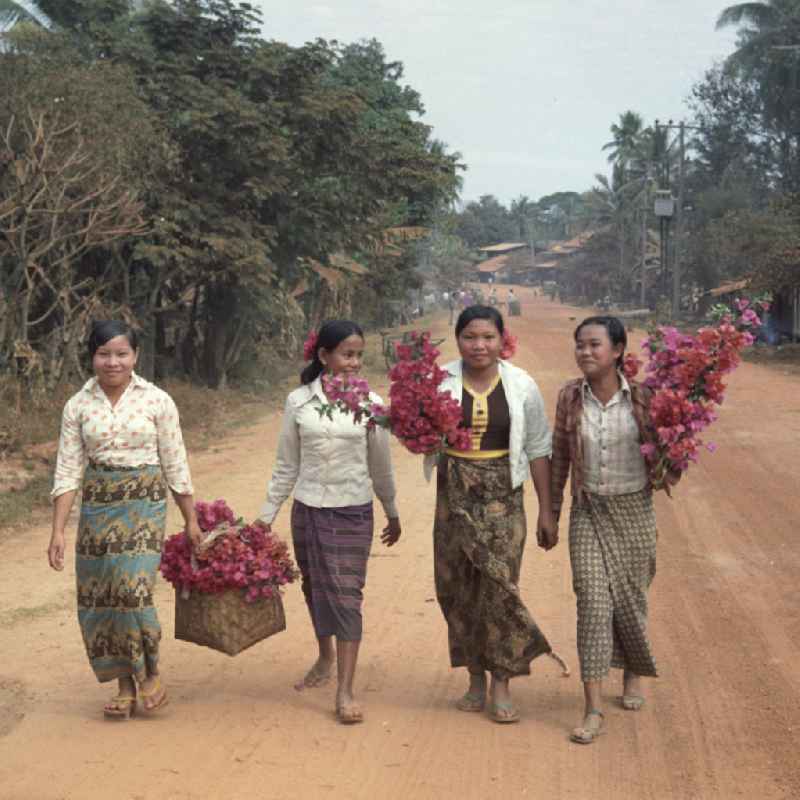 Mädchen mit Blumen auf einer Straße in der Demokratischen Volksrepublik Laos.