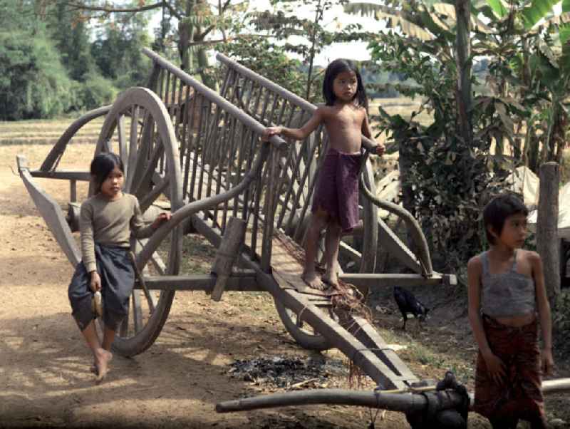 Kinder auf einem Karren in einem Dorf in der Demokratischen Volksrepublik Laos.