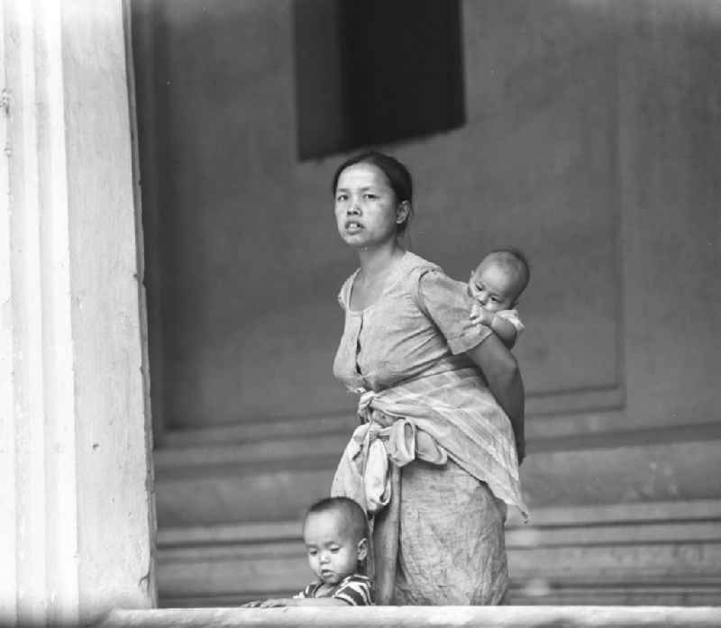 Frau mit zwei kleinen Kindern auf dem Arm in einem Haus in Vientiane in der Demokratischen Volksrepublik Laos.