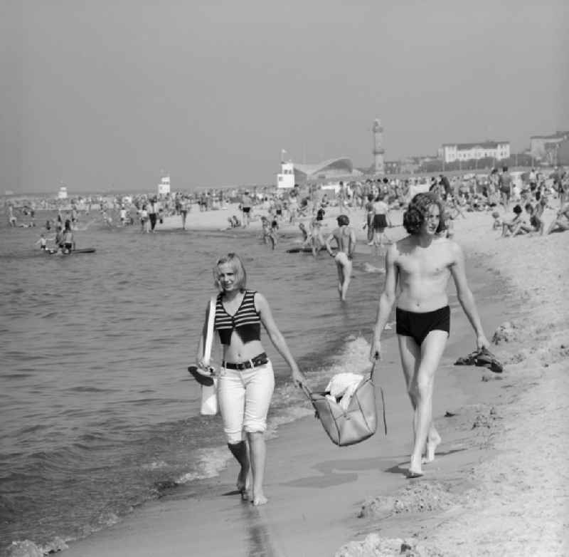 Young couple walking barefoot on the beach in the seaside resort of Warnemünde in Mecklenburg - Western Pomerania