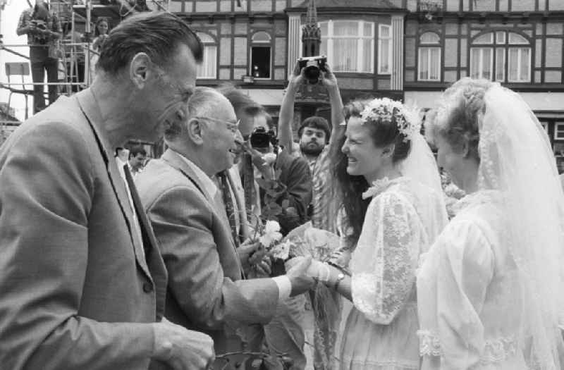 Kurt Hager, member of the Central Committee (ZK) and Political Bureau of the CC of the Socialist Unity Party of Germany (SED), and Werner Eberlein, member of the Politburo of the Central Committee of the SED, 1st secretary of the SED district administration Magdeburg, congratulate a bride on the marketplace after the wedding in Wernigerode in the state Saxony-Anhalt on the territory of the former GDR, German Democratic Republic