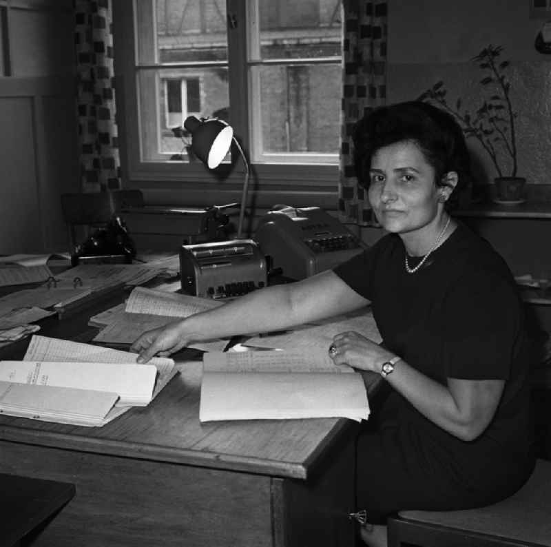 Elisabeth Schenk in der Verwaltung im Schwermaschienbau 'Heinrich Rau' in Wildau. Sie sitzt am Schreibtisch, Rechenmaschinen vom Typ Astra und Madix stehen auf Ihrem Tisch.