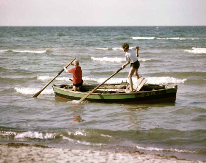Zwei Jungs unternehmen am Ostseestrand eine Bootspartie mit dem Ruderboot.